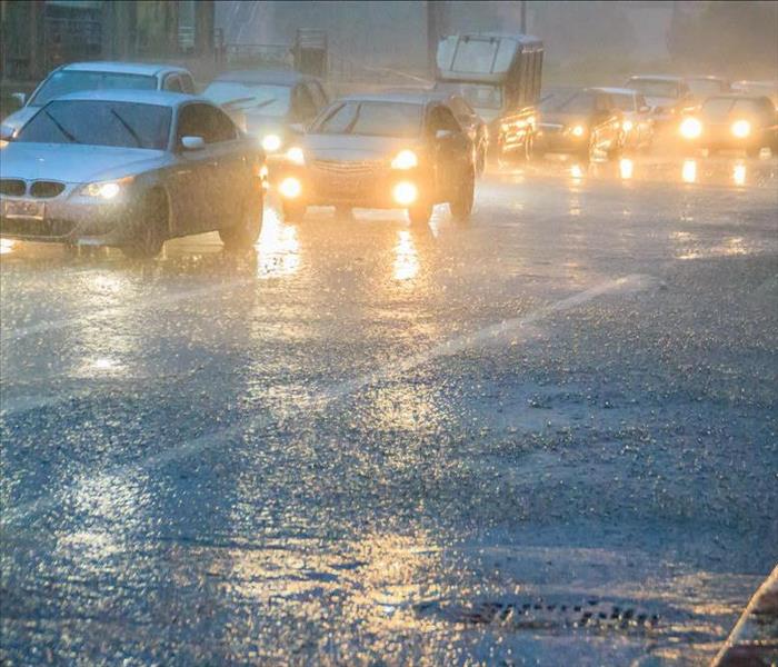 Cars driving on a busy road in heavy rain.