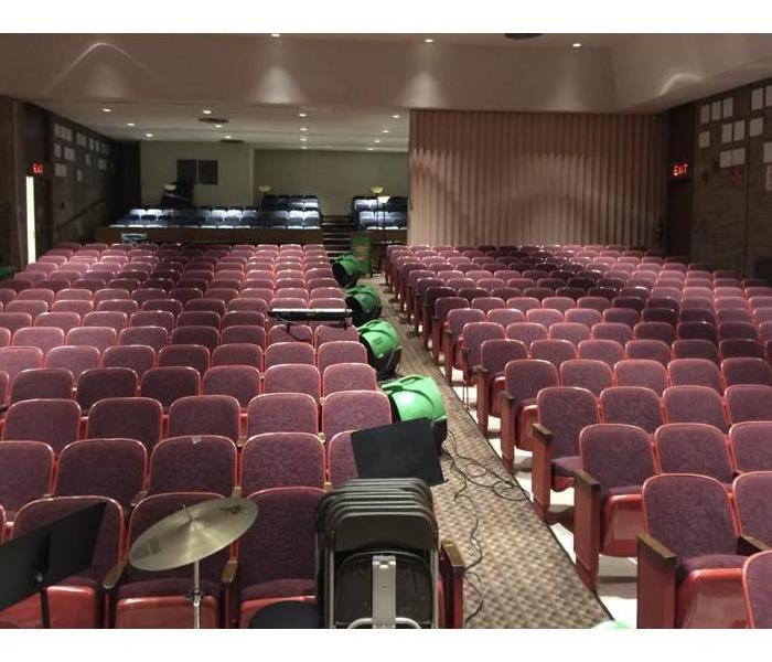 An auditorium with air movers and a dehumidifier set up to remove humidity from the room.
